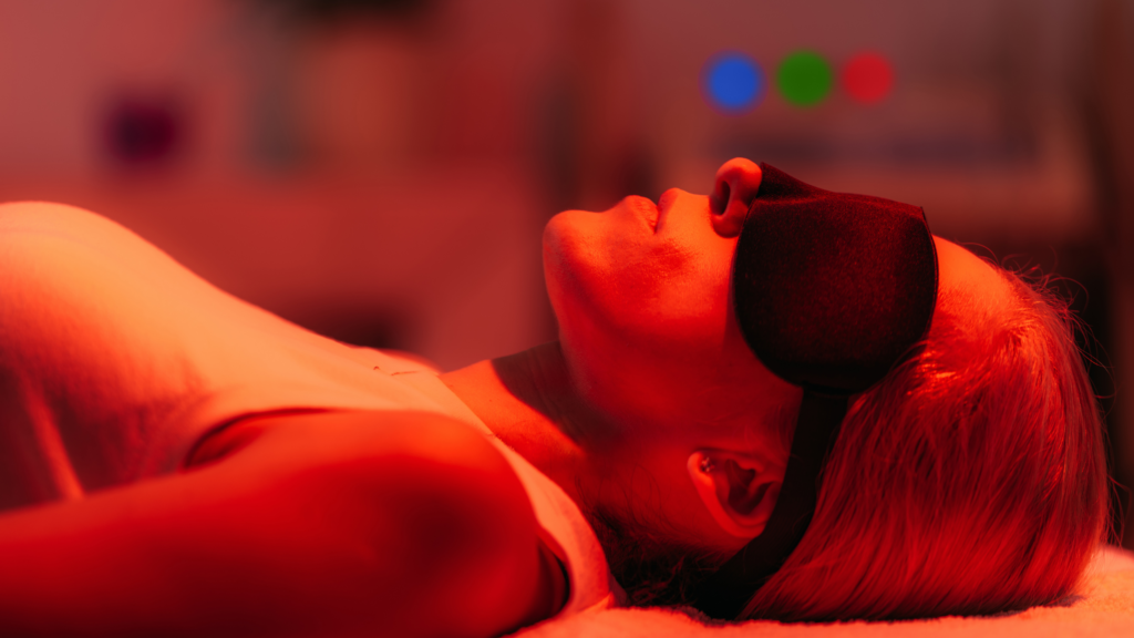 Woman relaxing with a black sleep mask in a warm red light.